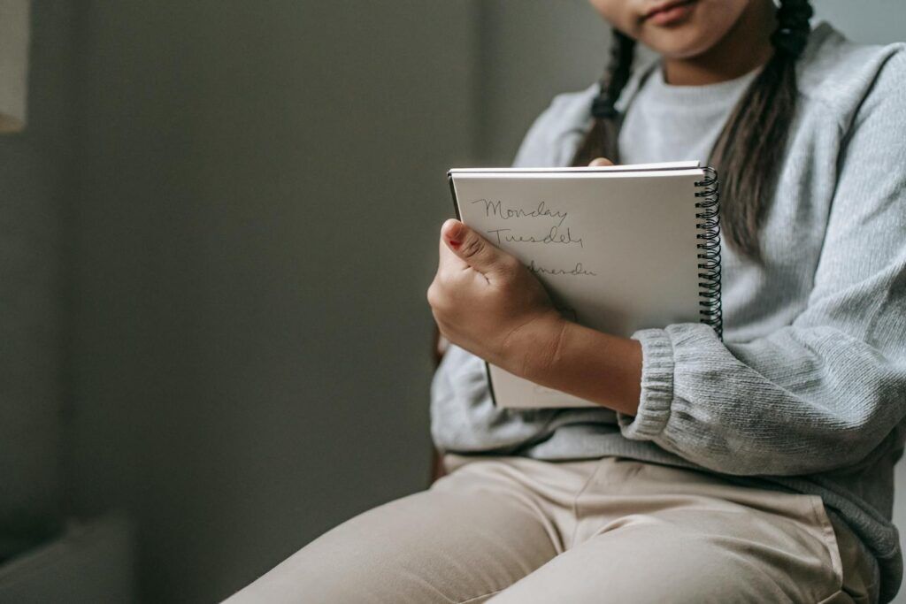 Die Kunst der Hausarbeit Fragestellung: Tipps und Tricks für deine wissenschaftliche Arbeit 3 Crop unrecognizable girl in casual outfit sitting on chair and taking notes in copybook