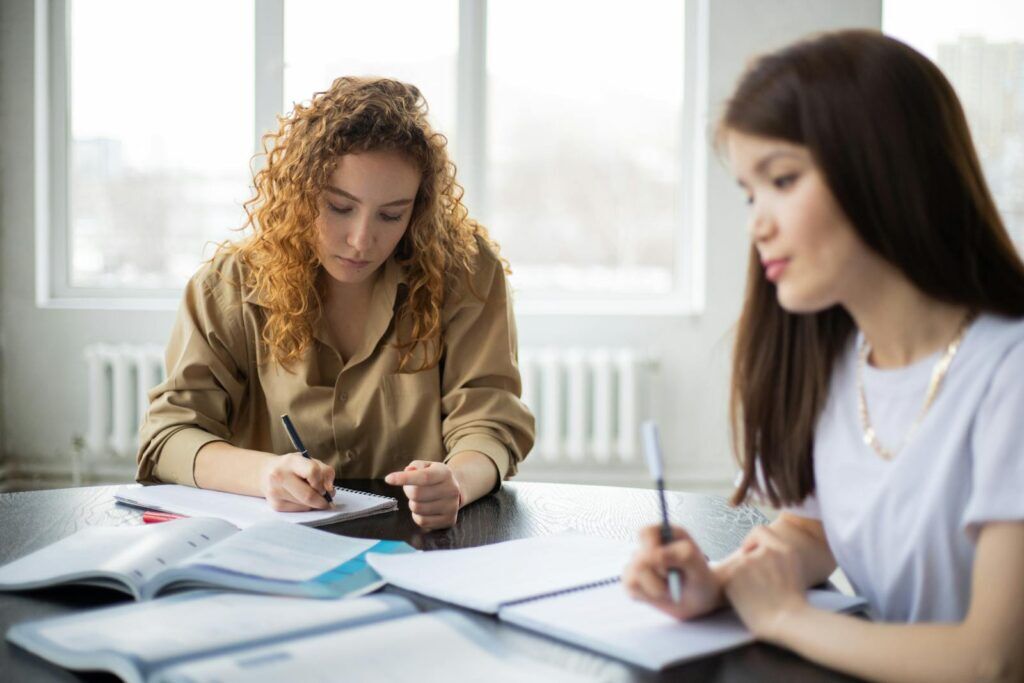 Professionelle Hausarbeit Korrektur: Perfektion für deine wissenschaftlichen Arbeiten 3 Focused students doing homework together in light workspace